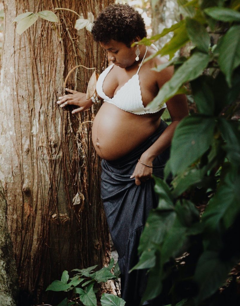 Pregnant woman in nature next to tree